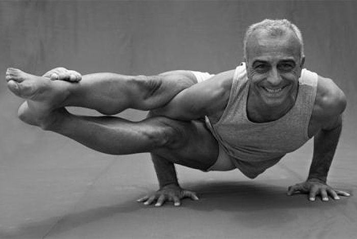 An arm balance with the legs extended forward, photographed in black and white.