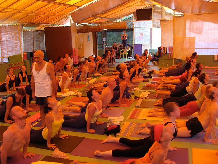 A large led class in the shala at Kovalam, students on coloured mats.