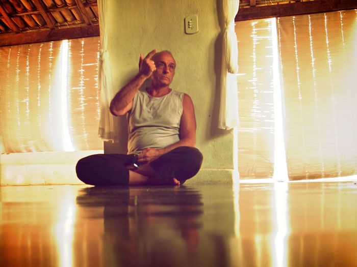 Lino Miele seated cross-legged on the shala floor, practising alternate nostril breathing.